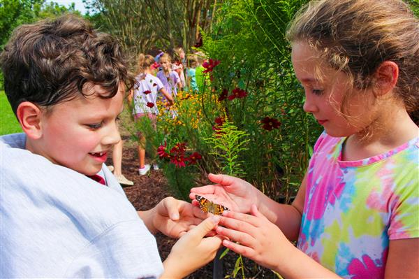 students in a flower garden with butterflies